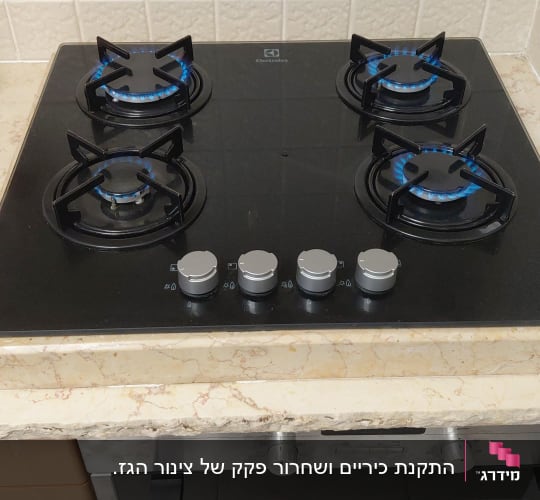 כיריים גז שחורות מותקנות במטבח עם ארבעה מבערים דולקים